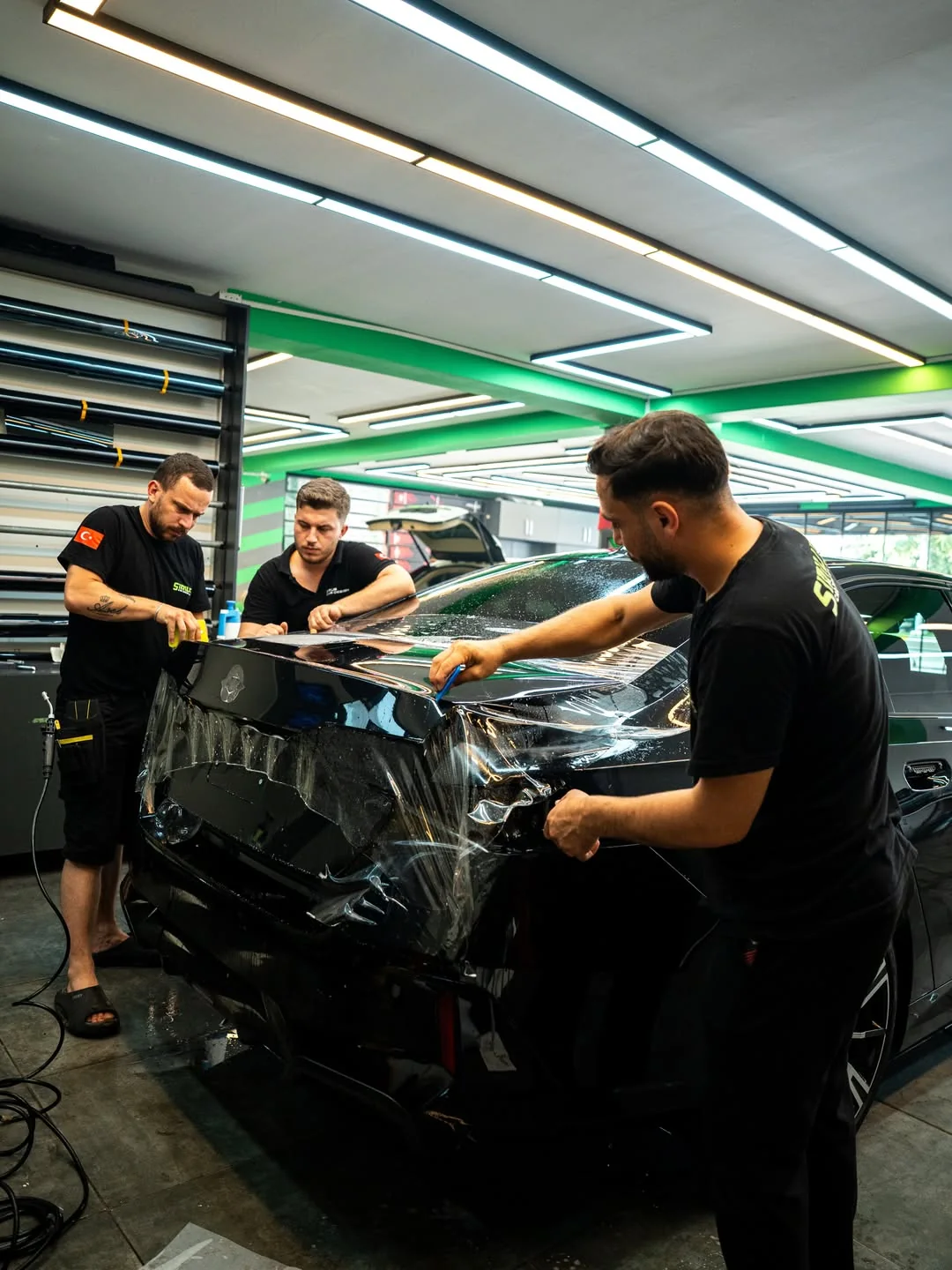 Sirius ekibi siyah BMW kaputuna koruyucu film uygularken